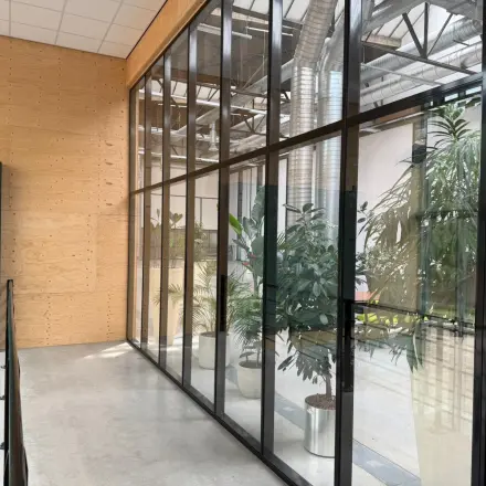Moderne kantoorruimte huren aan Scheepsbouwweg 29, Rotterdam Waalhaven met glazen wanden, planten en betonnen vloer.