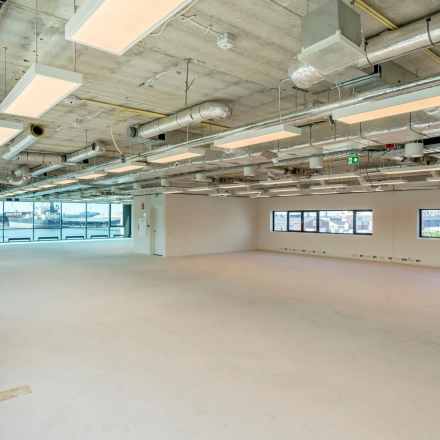 Ruime, lichte kantoorruimte in Rotterdam Waalhaven met grote ramen en modern industrieel plafond, ideaal voor het huren van diverse kantooropstellingen.