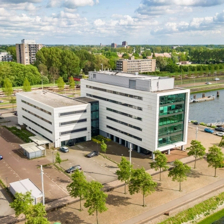 Luchtopname van een modern kantoorpand aan Waalhaven O.z. 85 in Rotterdam Waalhaven, met parkeerplaatsen en groene omgeving. Kantoorruimte huren in een stedelijke setting nabij het water.