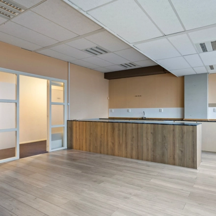 Interieur van een leeg kantoor op de Brauwweg 52-66, Schiedam, met lichte muren, houten vloer en ingebouwde kast; kantoorruimte huren mogelijk.