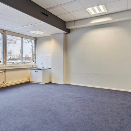 Leeg kantoorpand aan de Brauwweg 52-66 in Schiedam met zicht op grote ramen en wastafel.
