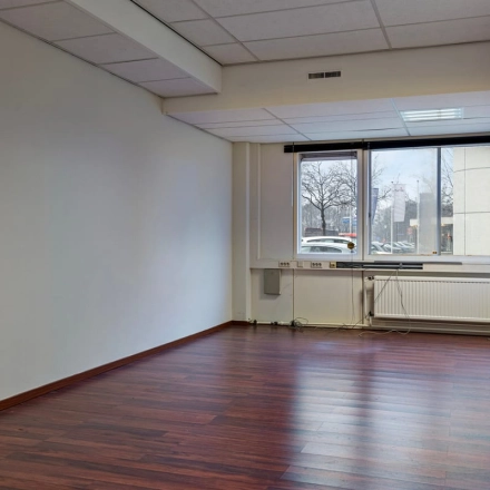 Ongemeubileerde kantoorruimte op de Brauwweg 52-66 in Schiedam met houten vloeren en een raam met uitzicht naar buiten.