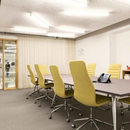 Moderne vergaderruimte in kantoorpand Schiphol Airport met gele stoelen rond een grote tafel, geschikt voor kantoorruimte huren.