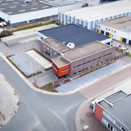 Luchtfoto van een kantoorpand op Fischerpad 106 in Sittard, omgeven door parkeerplaatsen en bedrijfsgebouwen.