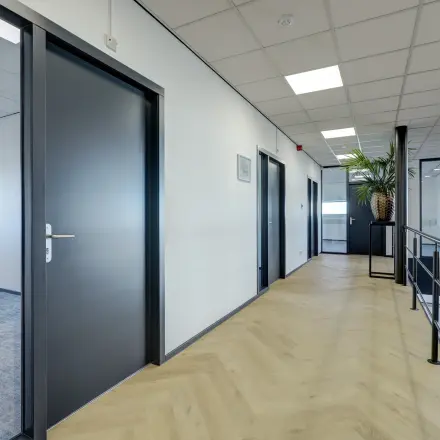 Strakke kantoorhal op Fischerpad 106 in Sittard met houten vloer en meerdere toegangsdeuren, ideaal voor kantoorruimte huren.