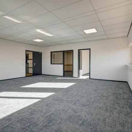 Leeg kantoor in Sittard met ramen en tapijt, klaar om te huren als werkruimte in kantoorpand.