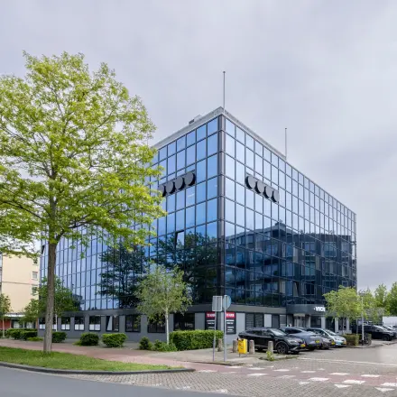 Modern kantoorpand aan de Curieweg 9 in Spijkenisse met een strakke glazen gevel en parkeermogelijkheden, ideaal voor wie kantoorruimte wil huren.