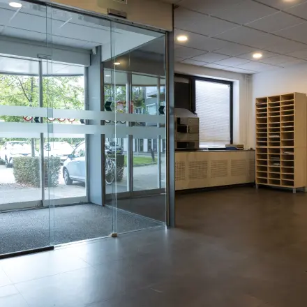 Ingang van een kantoorpand op Curieweg 9, Spijkenisse. Moderne glazen schuifdeuren en een overzichtelijke opstelling zorgen voor een uitnodigende entree voor wie kantoorruimte wil huren.