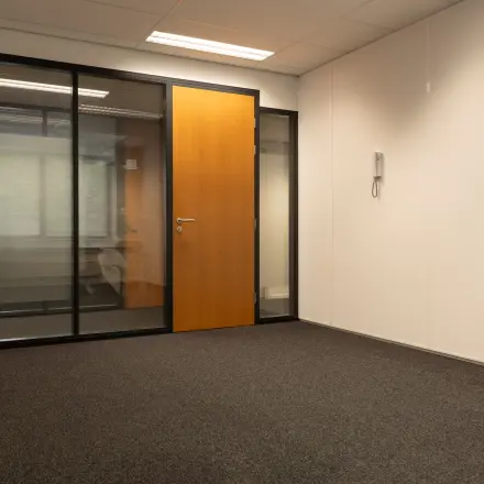 Lichte kantoorruimte in Spijkenisse met glazen wand en houten deur, ideaal voor wie kantoorruimte wil huren op Curieweg 9.