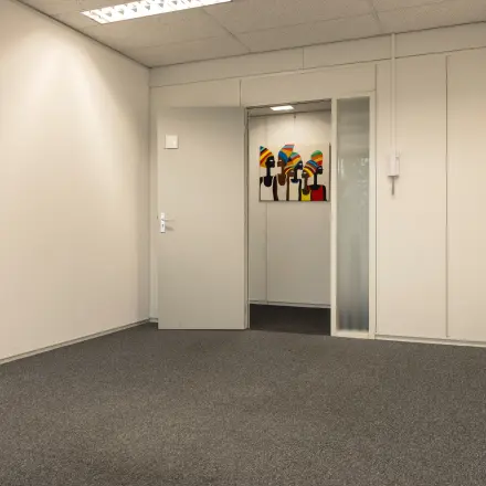 Onthullend kantoorpand op Curieweg 9 in Spijkenisse voor wie kantoorruimte wil huren; de ruimte is ongemeubileerd met tapijt en kunst aan de muur.