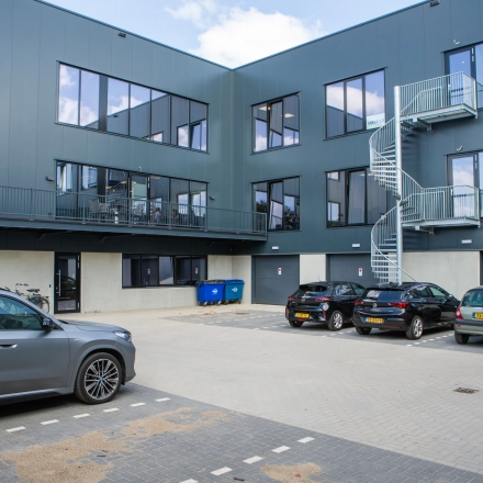 Buitenaanzicht van een modern kantoorpand op Kapitein Rondairestraat 8 in Tilburg met meerdere parkeerplaatsen voor de deur.