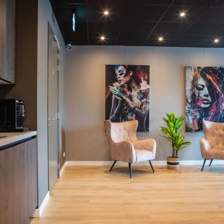 Kantoorruimte met moderne inrichting aan de Kapitein Rondairestraat 8 in Tilburg, voorzien van comfortabele fauteuils, kunst aan de muur en een klein keukenblok. Ideaal om een kantoor te huren.