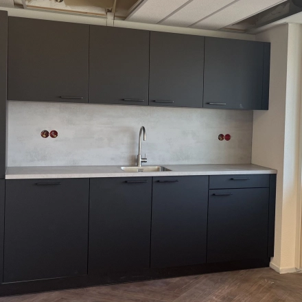 Kantoorruimte te huur met moderne pantry op Jaarbeursplein 22, Utrecht Centraal Station. Voorzien van donkergrijze kasten en een gootsteen.