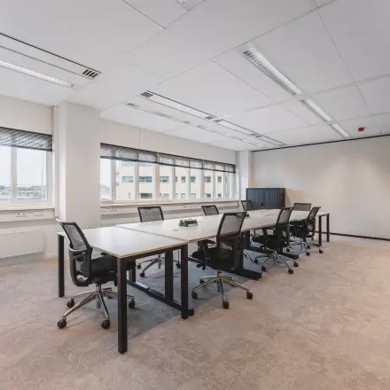 Lichte, moderne kantoorruimte met lange tafel en comfortabele stoelen, ideaal voor werkoverleggen. Grote ramen bieden uitzicht op Utrecht Centraal Station. Beschikbaar voor kantoorruimte huren op Leidseveer 2-10.