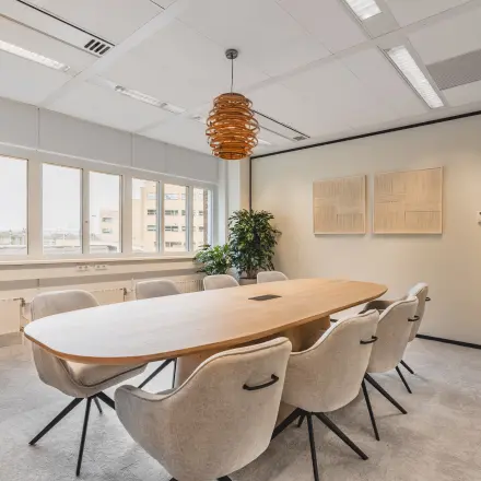 Moderne vergaderruimte in het kantoorpand aan Leidseveer 2-10 nabij Utrecht Centraal Station. De ruimte heeft een grote tafel met comfortabele stoelen en decoratieve elementen. Ideaal voor kantoorruimte huren.