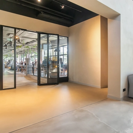 Moderne kantoorruimte te huur op Atoomweg 63 in Utrecht Lage Weide met glazen wanden, een loungehoek, en zicht op een levendige werkruimte. Stijlvolle verlichting en natuurlijke tinten versterken de open sfeer.