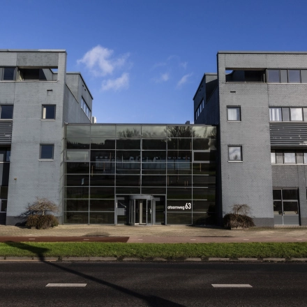 Het kantoorpand aan de Atoomweg 63 in Utrecht Lage Weide toont een modern gebouw met glazen entree en grijze gevel, ideaal voor kantoorruimte huren.