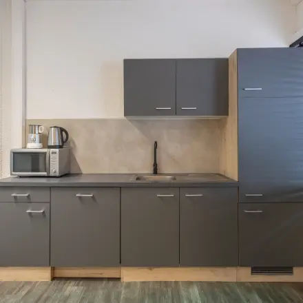 Functionele pantry in kantoorpand op Zonnebaan 18, Utrecht Lage Weide, beschikbaar voor kantoorruimte huren. Donkere kastjes en een kraan omgeven door neutrale tinten.