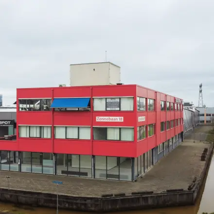 Rood kantoorpand aan Zonnebaan 18 in Utrecht Lage Weide met meerdere verdiepingen en grote ramen, ideaal voor bedrijven die kantoorruimte willen huren of kantoren willen verkennen in dit bedrijventerrein.