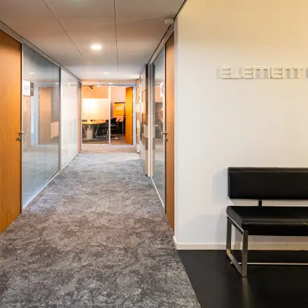 Kantoorruimte huren in Utrecht Leidsche Rijn bij Middenburcht 136, met een strakke gang en zitgedeelte. Glazen deuren leiden naar kantoren, wat een moderne, professionele uitstraling biedt.