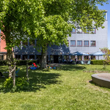Buitenkant van het kantoorpand aan de Goeman Borgesiuslaan 77 in Utrecht Noord, met een tuin en enkele mensen die buiten werken.