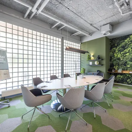 Moderne vergaderruimte in een kantoorpand aan de Goeman Borgesiuslaan 77, Utrecht Noord. De ruimte heeft groene accenten, een ovale tafel en comfortabele stoelen, ideaal voor kantoorruimte huren.