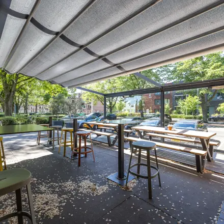 Kantoorruimte huren in Utrecht Noord met hoge tafels en krukken, uitkijkend op een groene omgeving. Ideaal voor informele bijeenkomsten of flexwerken.