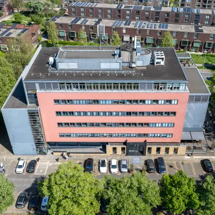 Luchtfoto van een kantoorpand op Goeman Borgesiuslaan 77, Utrecht Noord. Het gebouw heeft meerdere verdiepingen met parkeerplaatsen aan de voorkant. Ideaal voor kantoorruimte huren.