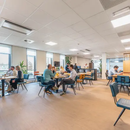 Kantoorruimte huren in Utrecht Papendorp, Orteliuslaan 850, met diverse mensen aan het werk en in overleg aan tafels in een open, lichte ruimte.