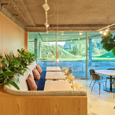 Moderne kantoorruimte met grote ramen, groene planten en zitplaatsen in een eigentijds kantoorpand in Utrecht. Geschikt voor bedrijven die kantoorruimte willen huren op Van Deventerlaan 30-40.