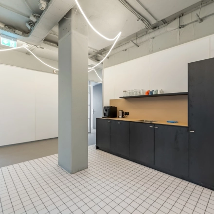 Kantoorruimte op Daltonlaan 200 in Utrecht Rijnsweerd met een strakke pantry met zwarte kasten, witte tegels en lichte muren, ideaal voor kantoorruimte huren.