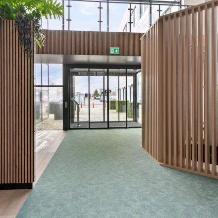 Moderne ingang van kantoorpand De Run 4312 in Veldhoven met ruime doorgang, natuurlijke lichtinval, en houtaccenten voor een stijlvolle uitstraling. Ideaal voor bedrijven die kantoorruimte willen huren.