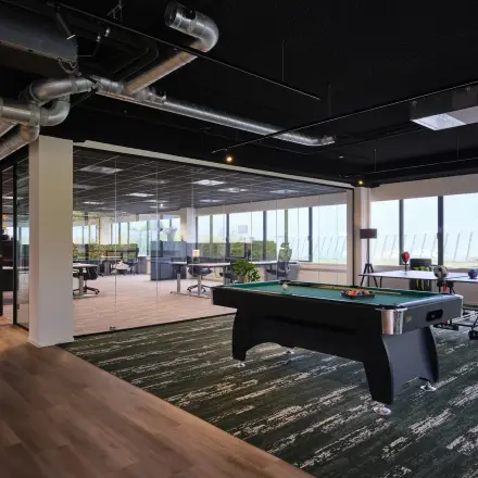 Moderne kantoorruimte op Havenweg 24 in Vianen Utr met stijlvolle inrichting, inclusief biljarttafel en uitzicht op een open werkvloer. Ideaal voor het huren van kantoren in een dynamisch kantoorpand.