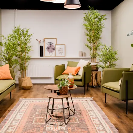 Stijlvolle kantoorruimte met groene banken, planten en decoratieve elementen, gelegen in een kantoorpand aan de Pelmolenlaan 16, Woerden. Ideaal voor bedrijven die kantoorruimte willen huren.