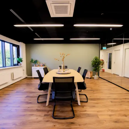 Moderne kantoorruimte op Pelmolenlaan 16, Woerden, met houten vloeren, een grote tafel en comfortabele stoelen. Ideaal voor vergaderingen of als flexibele werkruimte. Kantoorruimte huren in stijl.