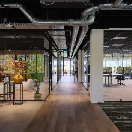 Moderne kantoorpand op Vijzelmolenlaan 9 in Woerden met glazen wanden, houten vloeren en planten voor een frisse uitstraling. Ideale kantoorruimte huren voor een professionele werkomgeving.