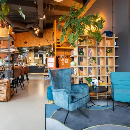 Moderne kantoorruimte huren op Boerhaavelaan 40, Zoetermeer, met stijlvolle meubelen, open planken en plantdecoratie. Gezellige zithoek en bijpassend interieur. Ideaal voor zakelijke bijeenkomsten.