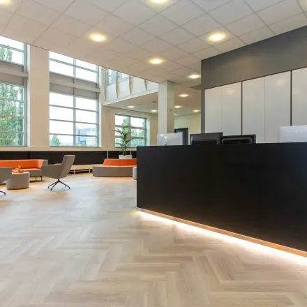 Ruime en lichte entree van een kantoorpand aan de Louis Braillelaan 80, Zoetermeer. Grote ramen verlichten de stijlvolle receptieruimte die uitnodigt tot kantoorruimte huren.