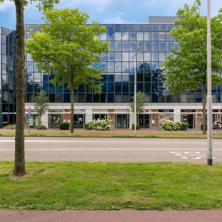 Modern kantoorpand aan Stationsplein 4 in Zwijndrecht met glazen gevel en groene omgeving, ideaal voor kantoorruimte huren.