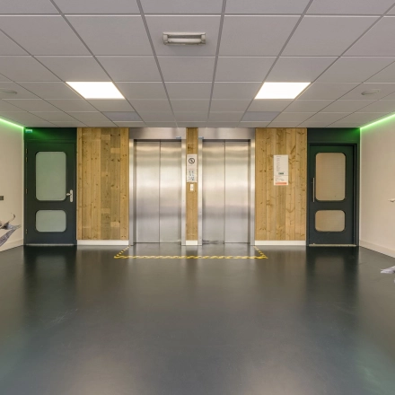 Binnenkant van het kantoorpand op Stationsplein 4 in Zwijndrecht, met een moderne lift en groene verlichting, ideaal voor wie kantoorruimte wil huren.