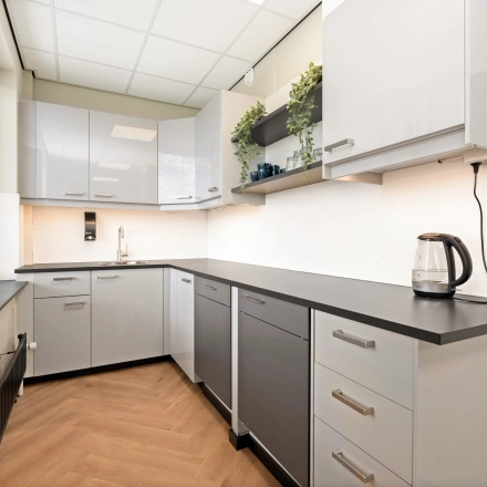 Moderne pantry met strakke kasten en voldoende ruimte, ideaal voor een korte pauze in het kantoorpand op Stationsplein 4, Zwijndrecht. Geschikt voor bedrijven die kantoorruimte huren.