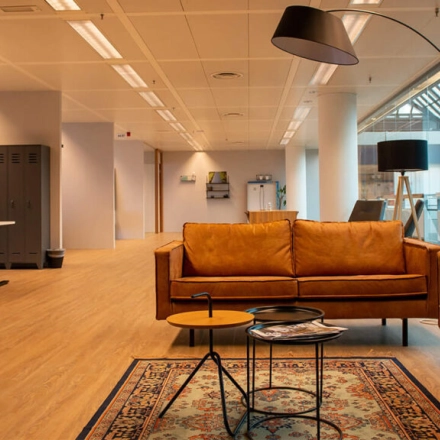 Moderne kantoorruimte op Zwartewaterallee 48 in Zwolle met stijlvolle leren banken, bijzettafels en een vloerkleed, ideaal voor informeel overleg of pauzes tijdens het huren van kantoor.