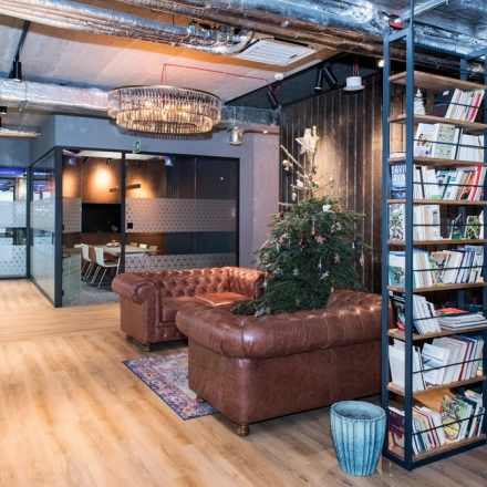 Nowoczesne biuro do wynajęcia na Wadowickiej 7 w Kraków Podgórze, z eleganckimi, umeblowanymi przestrzeniami biurowymi, w tym wygodnym lounge i imponującą biblioteczką.