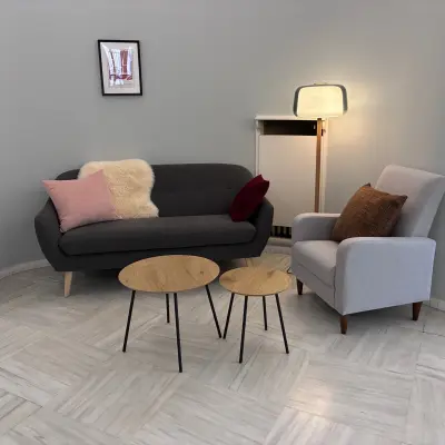 Gezellige loungehoek in kantoor te huur op Avenue Palmerston 3, Brussel Europese Wijk. Grijze zitbank met kussens, bijzettafels en een staande lamp, ideaal voor ontspanningsmomenten.