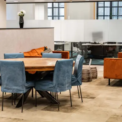 Moderne kantoorruimte te huur in Brussel Europese Wijk met stijlvolle, blauwe stoelen en een grote houten tafel. Perfect om kantoorruimte te huren op Rue des Colonies 56.
