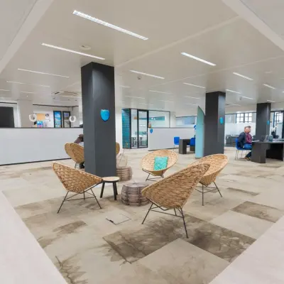 Kantoorruimte te huur in Brussel Europese Wijk met moderne werkplekken en informele zitgedeelte. Twee personen voeren zakelijke activiteiten uit aan een lang bureau.