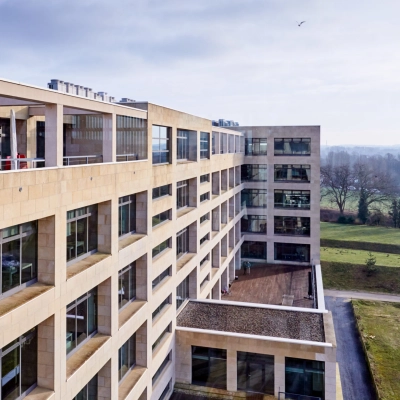 Buitenzijde van een groot kantoor te huur op Philipssite 5 in Leuven met moderne architectuur en veel ramen omgeven door groen.