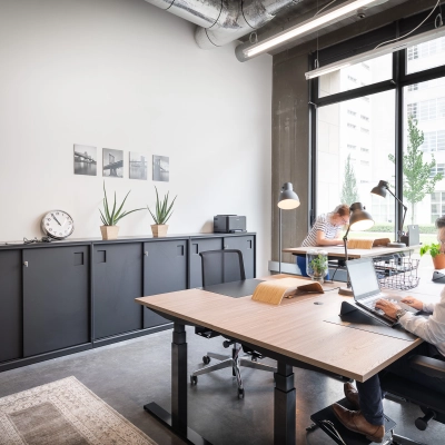 Moderne kantoorruimte te huur in Leuven op Philipssite 5, met strakke meubels en grote ramen die veel licht binnenlaten. Mensen zijn aan het werk, bezig op hun laptops. Ideaal voor wie een kantoorruimte wil huren.