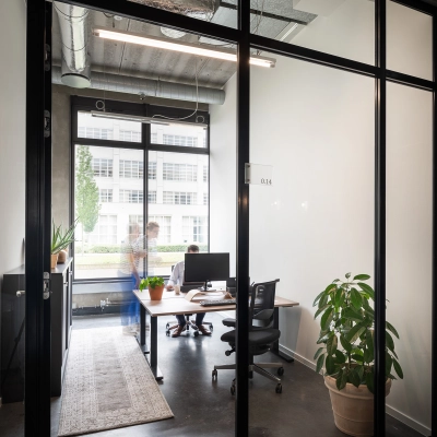 Kantoor te huur in Leuven op Philipssite 5 met grote ramen, strakke meubels en een gezellige plant. Ideaal voor professionals die kantoorruimte huren zoeken.