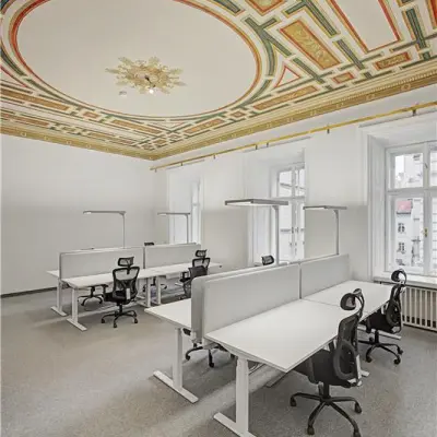 Elegante Bürofläche mieten in 1010 Wien mit dekorativer Decke und modernen Arbeitsplätzen, ideal für Kreativteams.